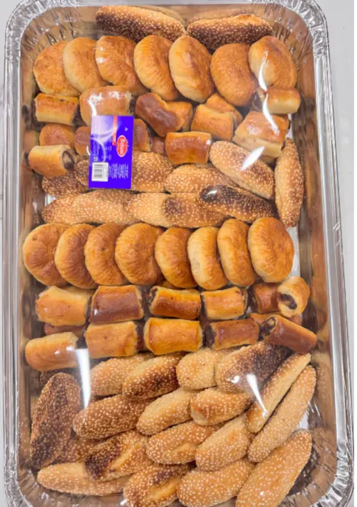 Assorted kulicha — sesame-topped golden bread rolls in mixed shapes.