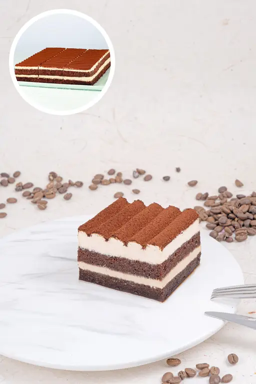 Square tiramisu mono cake with cream and a cocoa-dusted top.