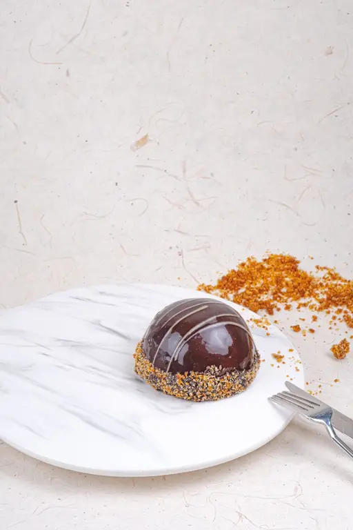 Glazed chocolate dome mono cake on a caramelised nut base.